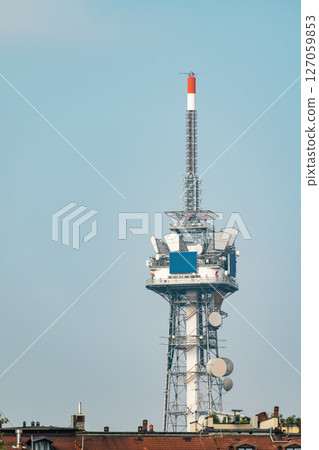 Tall communications and broadcast tower with satellite dishes on the rooftop 127059853