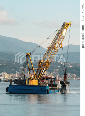 Floating crane dredger with grab bucket working in harbor Floating crane dredger with grab bucket working in harbor 127059860