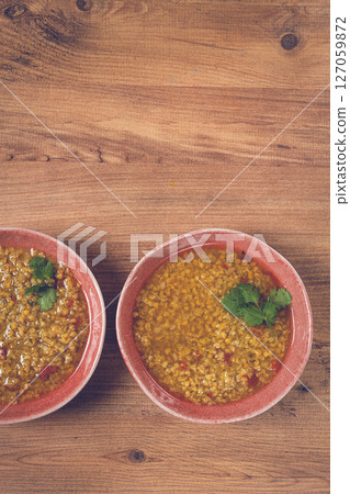Warm barley stew served in rustic bowls, garnished with fresh herbs, on a wooden table Warm barley stew served in rustic bowls, garnished with fresh herbs, on a wooden table 127059872