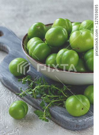 Tkemali, green cherry plum, in a bowl, on a gray table, top view, natural light, no people, 127059895