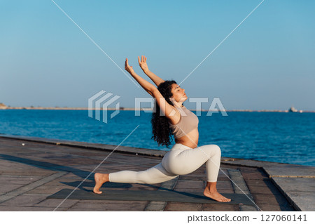Athletic woman doing gymnastics yoga asana on the beach by the sea Athletic woman doing gymnastics yoga asana on the beach by the sea 127060141