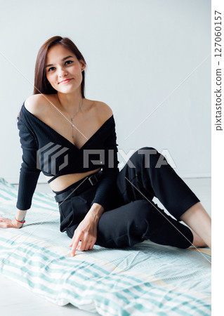 Slim fashion woman in black clothes sitting on the floor 127060157