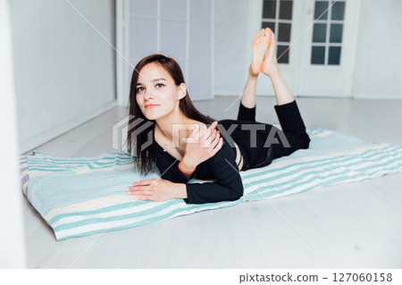 Slim fashionable woman in black clothes lying on mattress 127060158