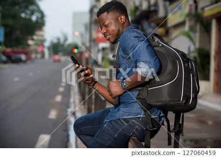 portrait of young african man with mobile phone, smiling. 127060459