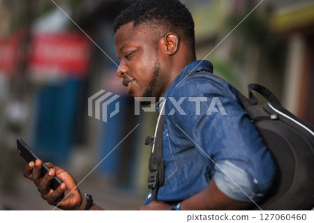 Close-up of young african man with mobile phone, smiling. Close-up of young african man with mobile phone, smiling. 127060460