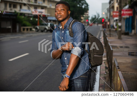 young man traveler waiting for a car at the bus stop 127060496