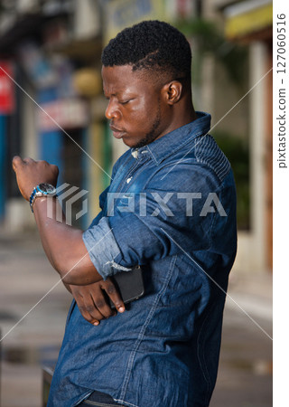 young man is watching the watch in his hand waiting for a late m 127060516