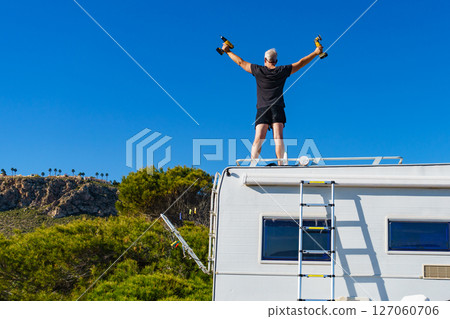 Man on roof of caravan. Repair motor home. 127060706