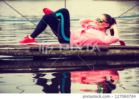 Girl training in sporty clothes on lake shore Girl training in sporty clothes on lake shore 127060784