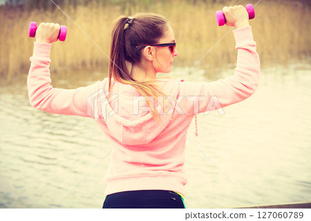 Woman exercising with dumbbells outdoor 127060789