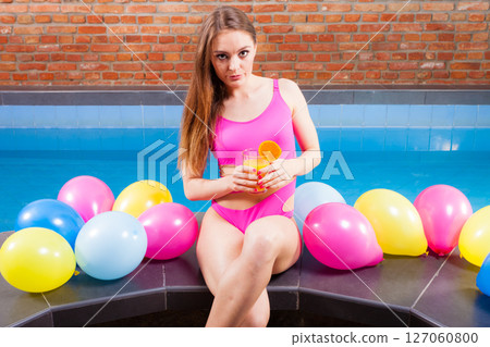 Woman with balloons and cocktail drink at swimming pool. 127060800