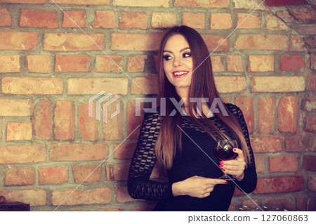 Woman tasting wine in rural cottage interior 127060863