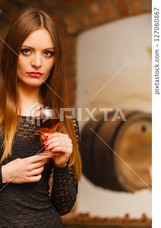 Woman tasting wine in rural cottage interior 127060867