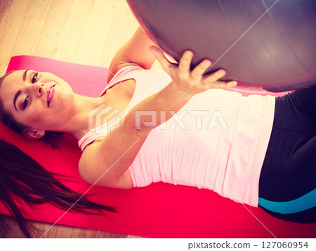 Young lady lying on the mat with fit ball. 127060954