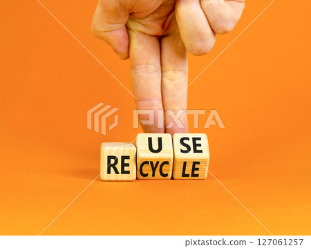 Reuse or recycle symbol. Concept words Reuse Recycle on wooden block. Beautiful orange table orange background. Businessman hand. Business reuse or recycle concept. Copy space. 127061257