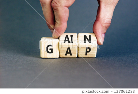 Gain or gap symbol. Concept words Gain Gap on wooden block. Beautiful grey table grey background. Businessman hand. Business gain or gap concept. Copy space. Gain or gap symbol. Concept words Gain Gap on wooden block. Beautiful grey table grey background. Businessman hand. Business gain or gap concept. Copy space. 127061258