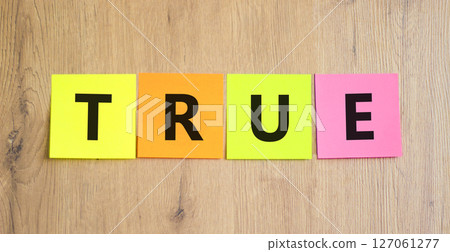 True symbol. Concept word True on beautiful colored paper. Beautiful wooden table wooden background. Business, lifestyle, support and true concept. Copy space. 127061277