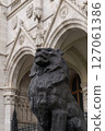 Bronze statue of a lion in front of the beautiful ancient building of the Hungarian Parliament in neo-gothic style 127061386