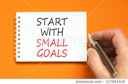 Start with small goals symbol. Concept words phrase Start with small goals on beautiful white note. Businessman's hand. Beautiful orange background. Business Start with small goals concept. Copy space 127061426