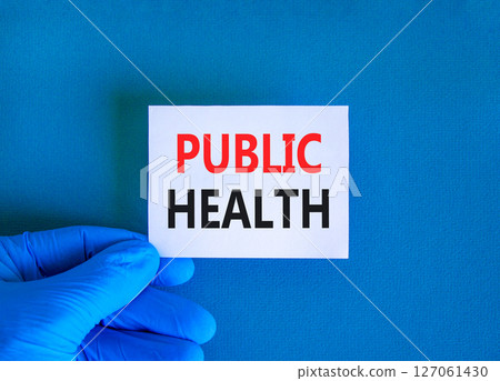 Public health symbol. Concept words Public health on beautiful white card. Doctor's hand in blue medical glove. Beautiful blue background. Medical healthy lifestyle public health concept. Public health symbol. Concept words Public health on beautiful white card. Doctor's hand in blue medical glove. Beautiful blue background. Medical healthy lifestyle public health concept. 127061430