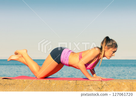 Woman doing sports exercises outdoors by seaside 127061720