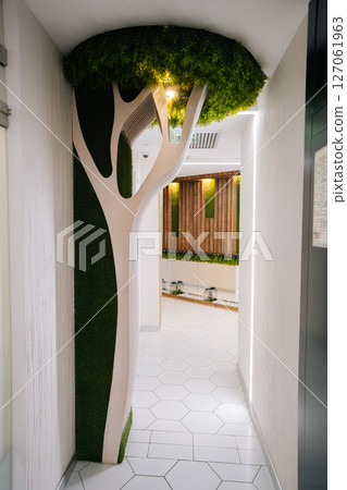 White artificial tree decorated with green moss creating unique atmosphere in modern beauty clinic interior, combining natural elements with contemporary design, no people, nobody, vertical shot. White artificial tree decorated with green moss creating unique atmosphere in modern beauty clinic interior, combining natural elements with contemporary design, no people, nobody, vertical shot. 127061963