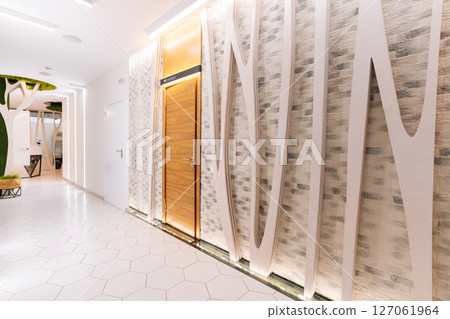 Empty corridor in modern beauty clinic featuring decorative brick tile wall, white curves and led lighting, creating welcoming and relaxing atmosphere, no people, nobody. 127061964