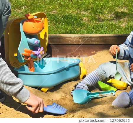 Children Playing in Backyard Sandbox with Colorful Toys 127062635