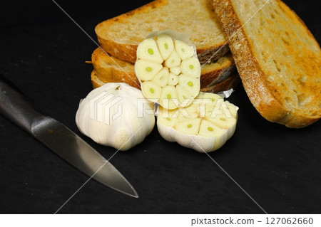 garlic and toasted bread slices on black background garlic and toasted bread slices on black background 127062660