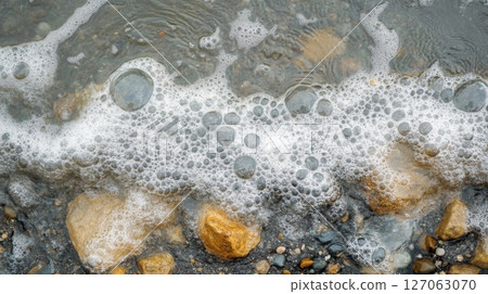 White Foam Bubbles on Water With Rocks and Gravel White Foam Bubbles on Water With Rocks and Gravel 127063070