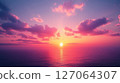 A breathtaking sunset over a tranquil ocean, showcasing vibrant pink and purple hues in the sky and water. 127064307