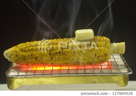 Cooking corn butter on a smoking charcoal grill 127064526