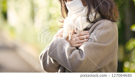 一名中年婦女穿著外套和口罩在鎮上行走 一名中年婦女穿著外套和口罩在鎮上行走 127064680