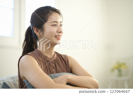 一位 20 多歲的女人坐在沙發上,美麗的形象 一位 20 多歲的女人坐在沙發上,美麗的形象 127064687