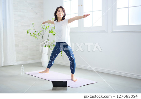 A woman in her 50s doing yoga in yoga wear 127065054