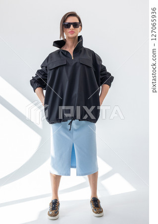 Elegant woman in black windbreaker jacket and light blue skirt on white background. Fashionable female style. Studio photography. Vertical photo. High quality photo Elegant woman in black windbreaker jacket and light blue skirt on white background. Fashionable female style. Studio photography. Vertical photo. High quality photo 127065936