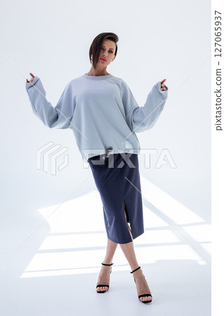 Beautiful woman in gray sweatshirt and black skirt on light background. Vertical photo. High quality photo Beautiful woman in gray sweatshirt and black skirt on light background. Vertical photo. High quality photo 127065937