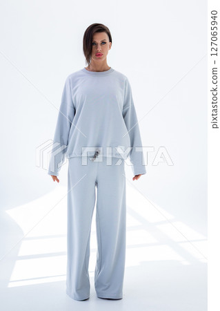 Young woman in gray sweatshirt and pants on white background. Studio photography. Vertical photo. High quality photo 127065940