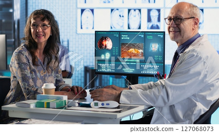 Doctor provides cancer screening guidance to a patient discussing MRI scans and tumor growth. Early detection and preventative medicine emphasized for better health outcomes. Camera B. Doctor provides cancer screening guidance to a patient discussing MRI scans and tumor growth. Early detection and preventative medicine emphasized for better health outcomes. Camera B. 127068073