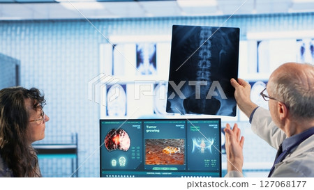 Oncology consultation takes place as a senior medic explains radiology scan, emphasizing preventive medicine and healthy lifestyle recommendations. Shares risk factors and causes. Camera B. Oncology consultation takes place as a senior medic explains radiology scan, emphasizing preventive medicine and healthy lifestyle recommendations. Shares risk factors and causes. Camera B. 127068177