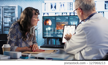 Healthcare professional sharing his expertise and interpreting the MRI scans results, offering advice and support to sick woman at checkup. Accurate diagnostics and patient care. Camera A. Healthcare professional sharing his expertise and interpreting the MRI scans results, offering advice and support to sick woman at checkup. Accurate diagnostics and patient care. Camera A. 127068213