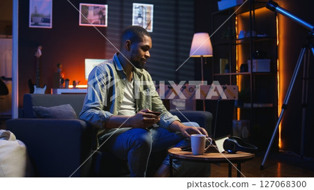 Young guy managing online banking and payments with the credit card, entering digits on website to confirm and oversee money transfer. Casual woman at home makes transactions. Camera A. Young guy managing online banking and payments with the credit card, entering digits on website to confirm and oversee money transfer. Casual woman at home makes transactions. Camera A. 127068300