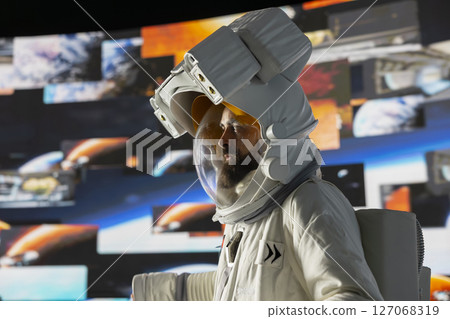 Curious astronaut standing on a distant planet in space suit and helmet, collecting a soil sample beneath a vast sky filled with stars. Exploring alien worlds and cosmic frontiers in a space craft. 127068319
