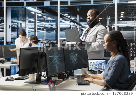 Data center IT experts using artificial intelligence neural networks technology. African american server farm facility software developers using AI programming language on computer to update hardware 127068389