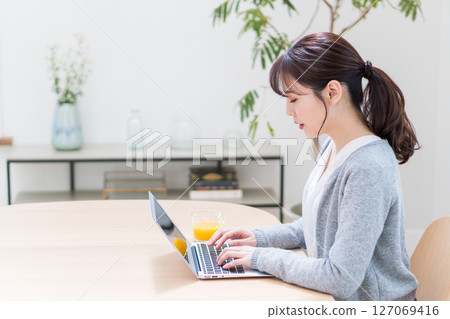 A woman teleworking in the living room. A woman teleworking in the living room. 127069416