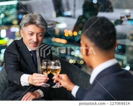 跨國商人在城市夜景的背景下舉杯 跨國商人在城市夜景的背景下舉杯 127069814