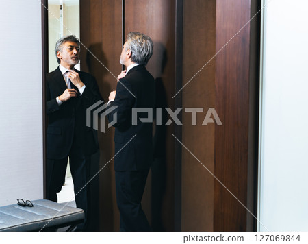 中年男子照著鏡子調整自己的外表 127069844