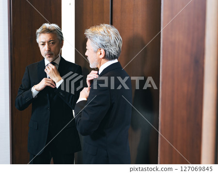 中年男子照著鏡子調整自己的外表 127069845