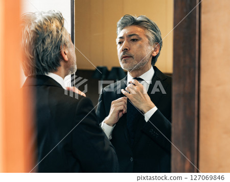 中年男子照著鏡子調整自己的外表 127069846