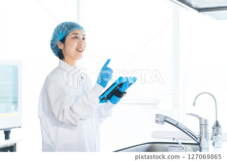A female worker in a sanitation lab coat checking the kitchen 127069865